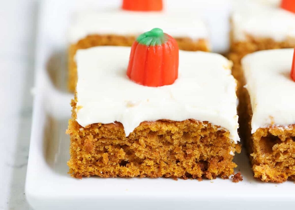 Sliced pumpkin bars with cream frostings on top. 