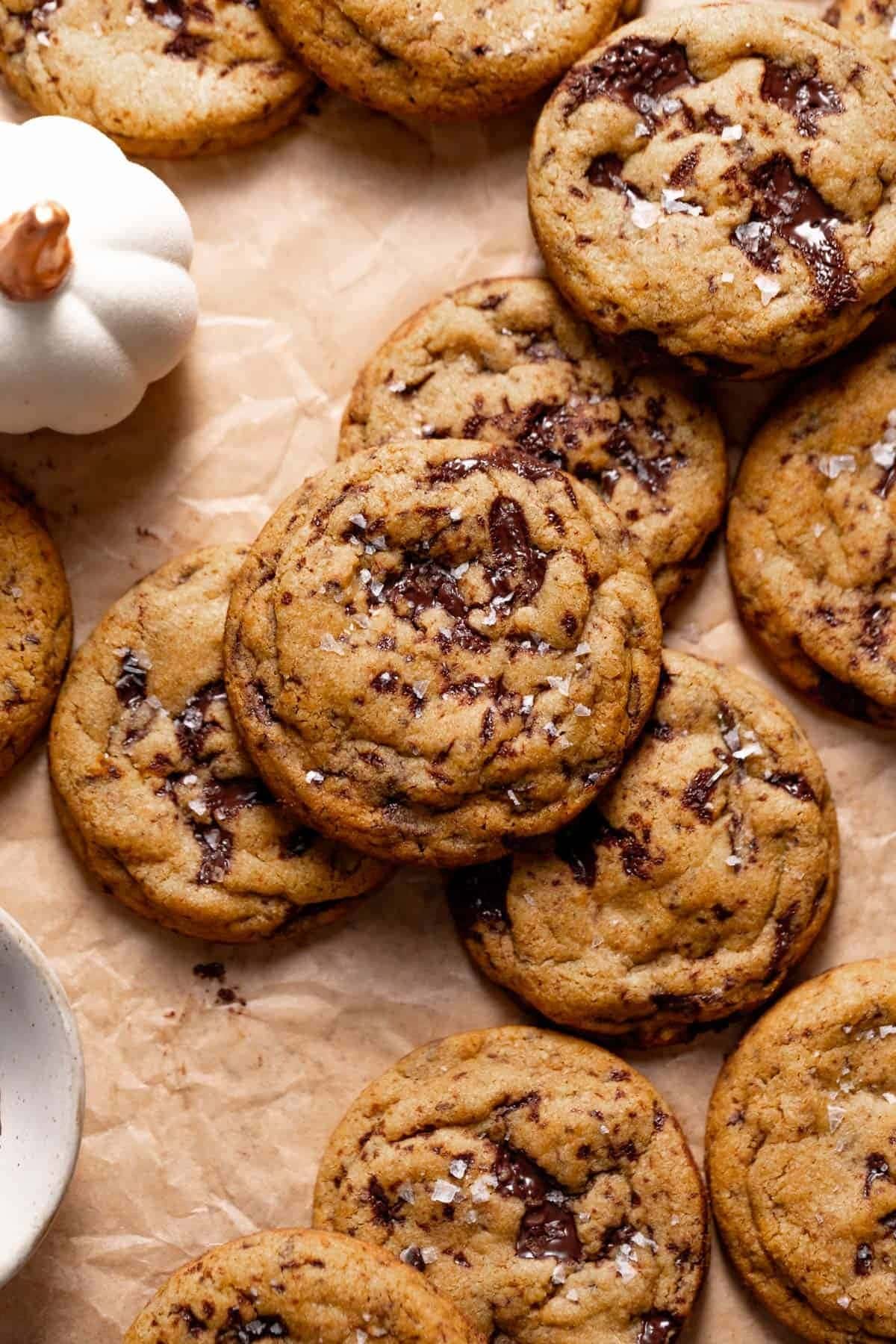 Pumpkin chocolate chip cookies on top of parchment paper sprinkled with rock salt. 