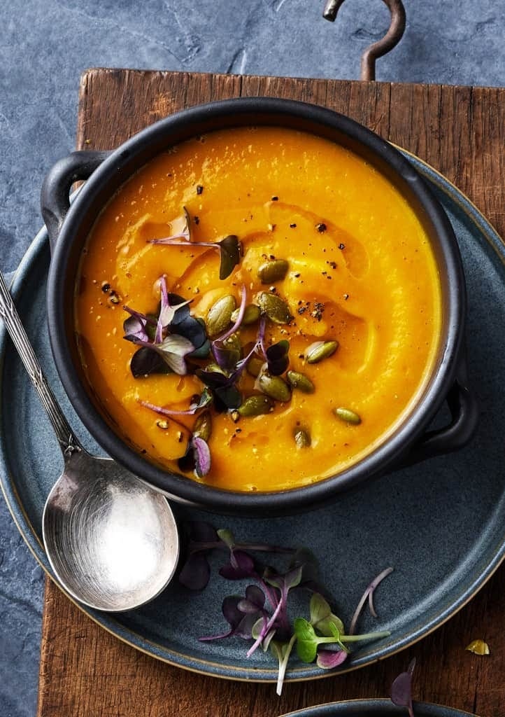 Bowl of homemade Roasted Acorn Squash Soup garnished with pepitas and microgreens