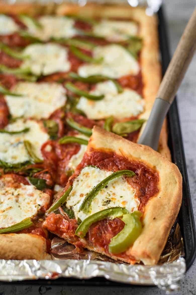 Sliced sheet pan pizza topped with cheese and bell pepper. 