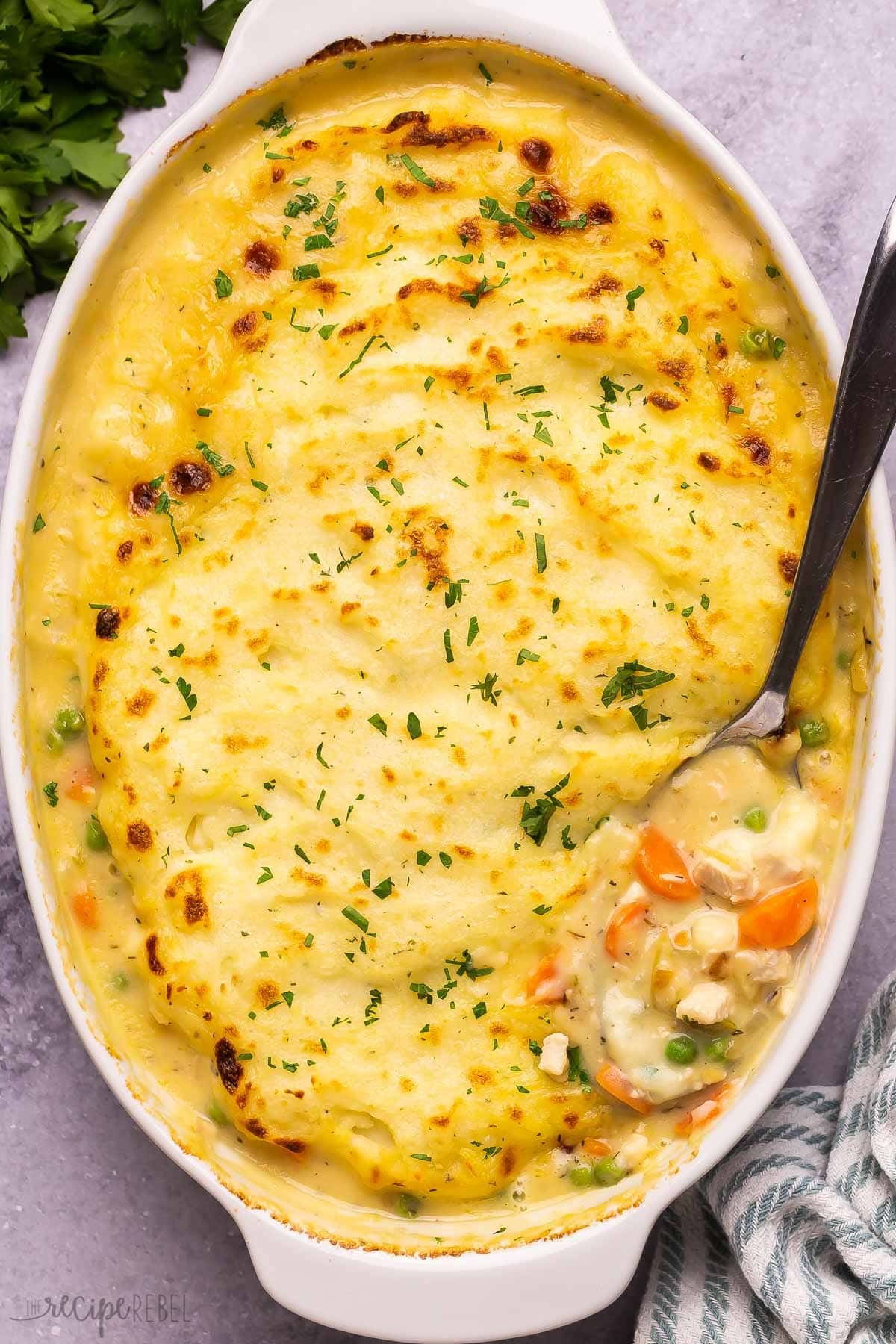 Turkey shepherd's pie in white casserole dish with spoon.