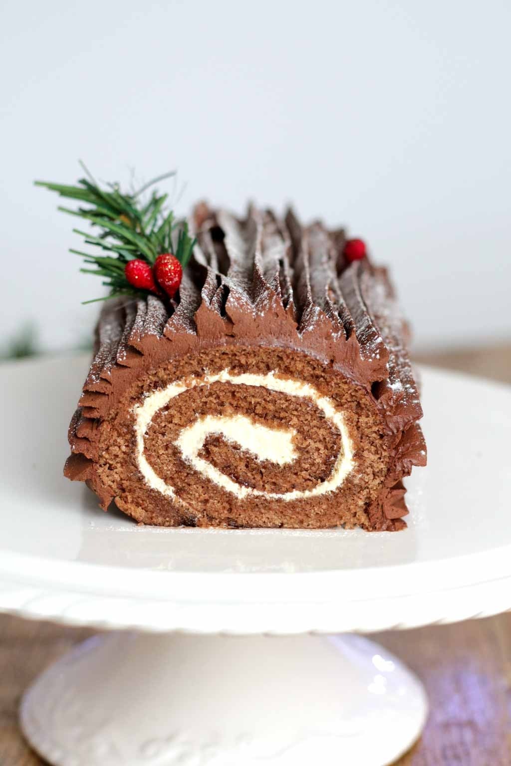 A chocolate roll with a cherry on top on a cake tray.