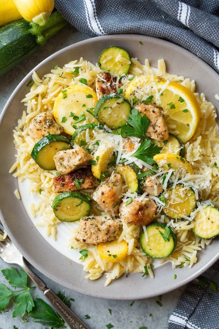 Skillet lemon parmesan chicken with zucchini and squash on a gray plate. 