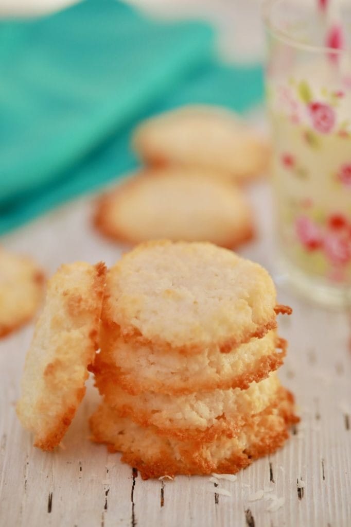 Shredded coconut cookies arranged in stack on top of wooden table. 