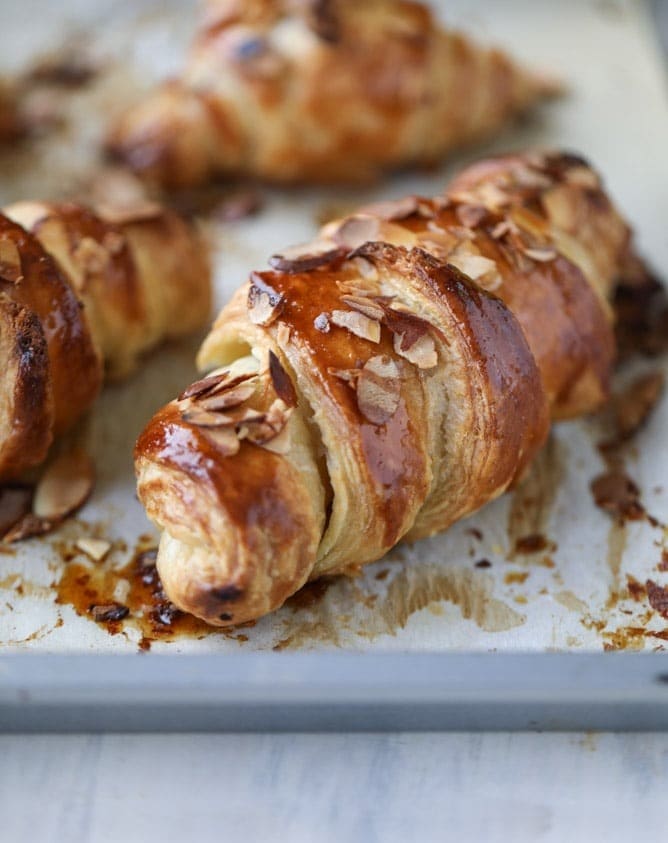 Toasted croissant topped with toasted almond on a sheet pan. 