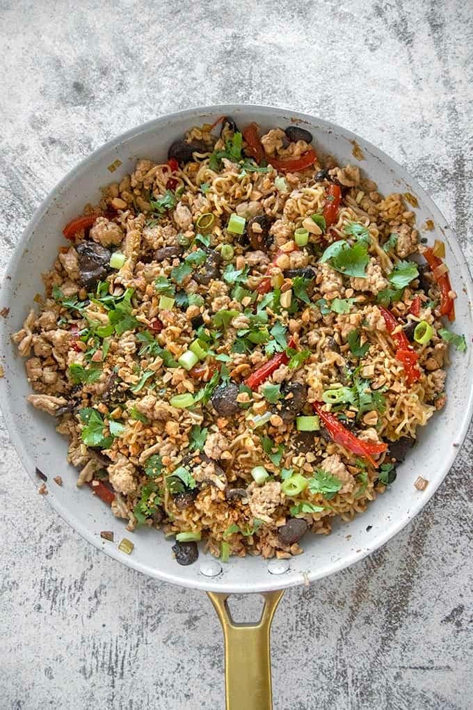 ground chicken served with noodles,edamame, broccoli, shredded carrots, chopped green beans, or asparagus cooked on a pan. 