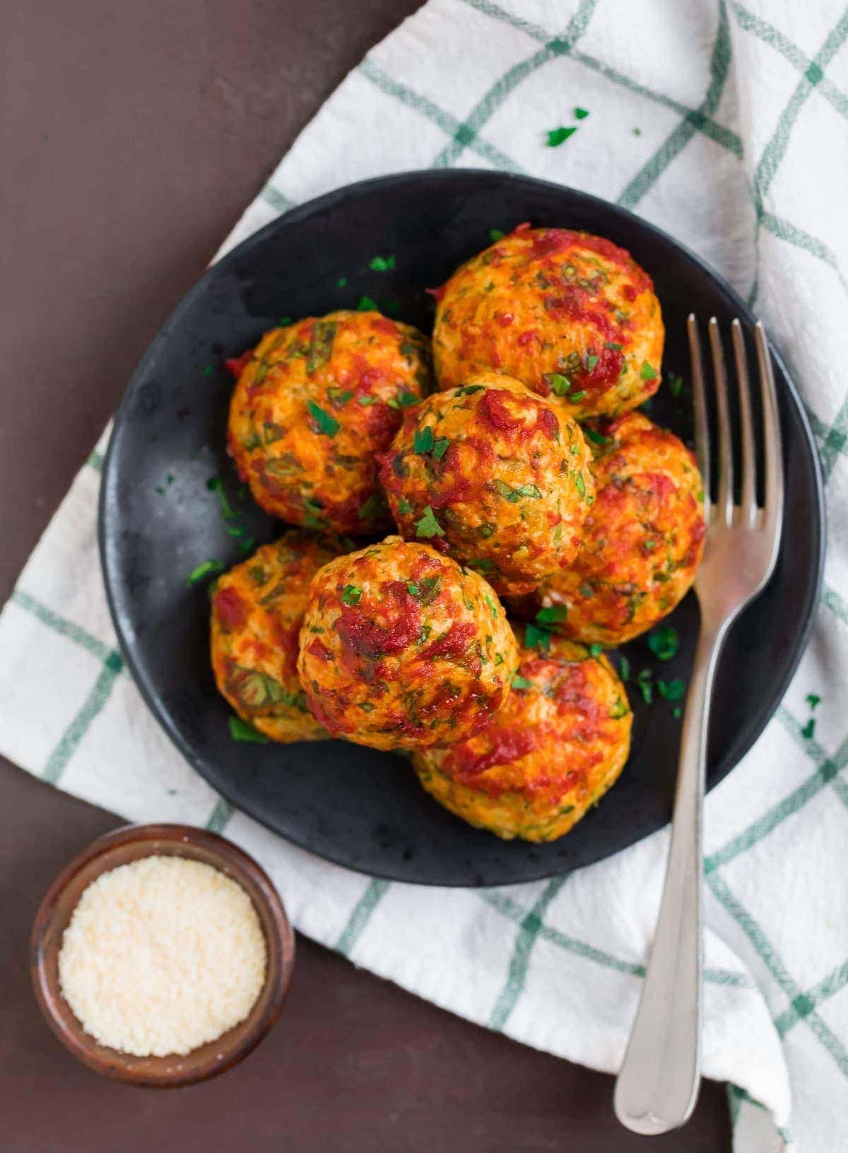 Chicken meatballs on a black plate with fork. 