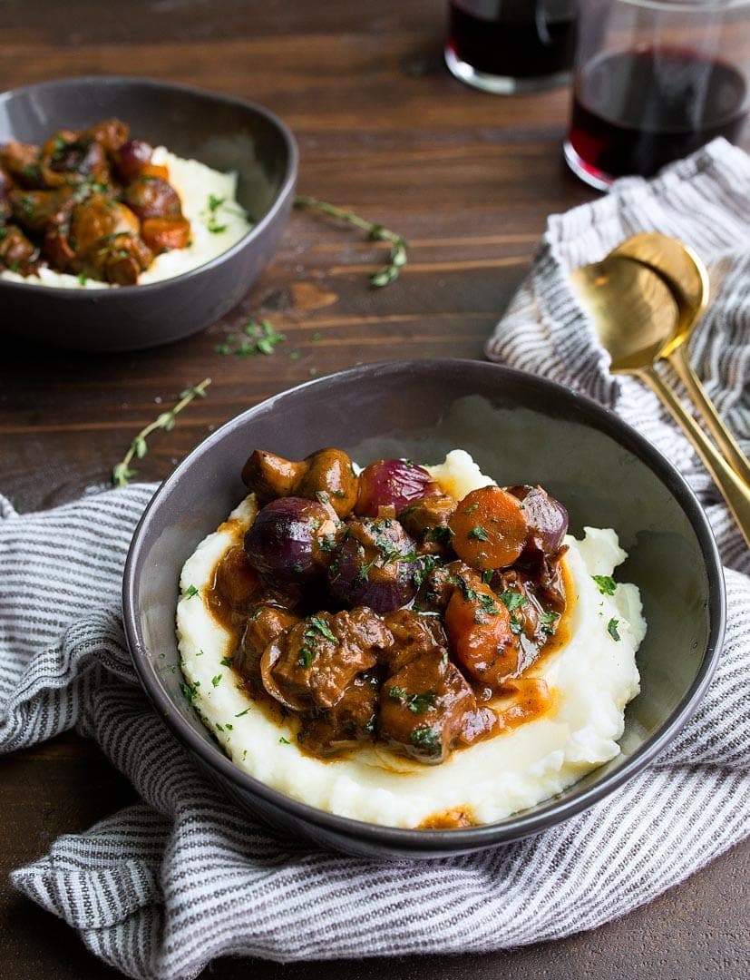 Beef bourguignon on a bowl served on top of mashed potatoes. 