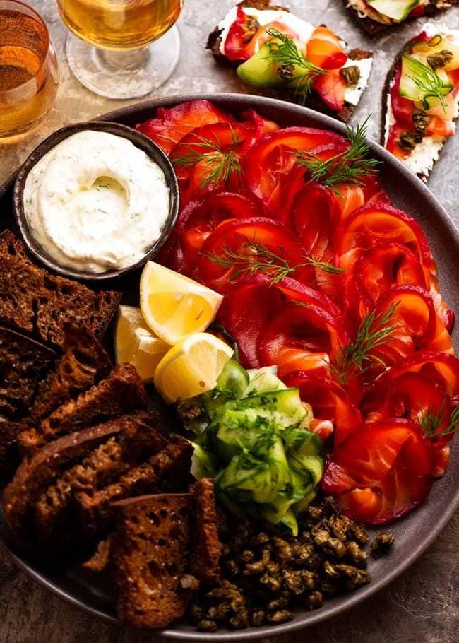 A platter of bread, cheese, and meat, with slices of beetroot-cured salmon.