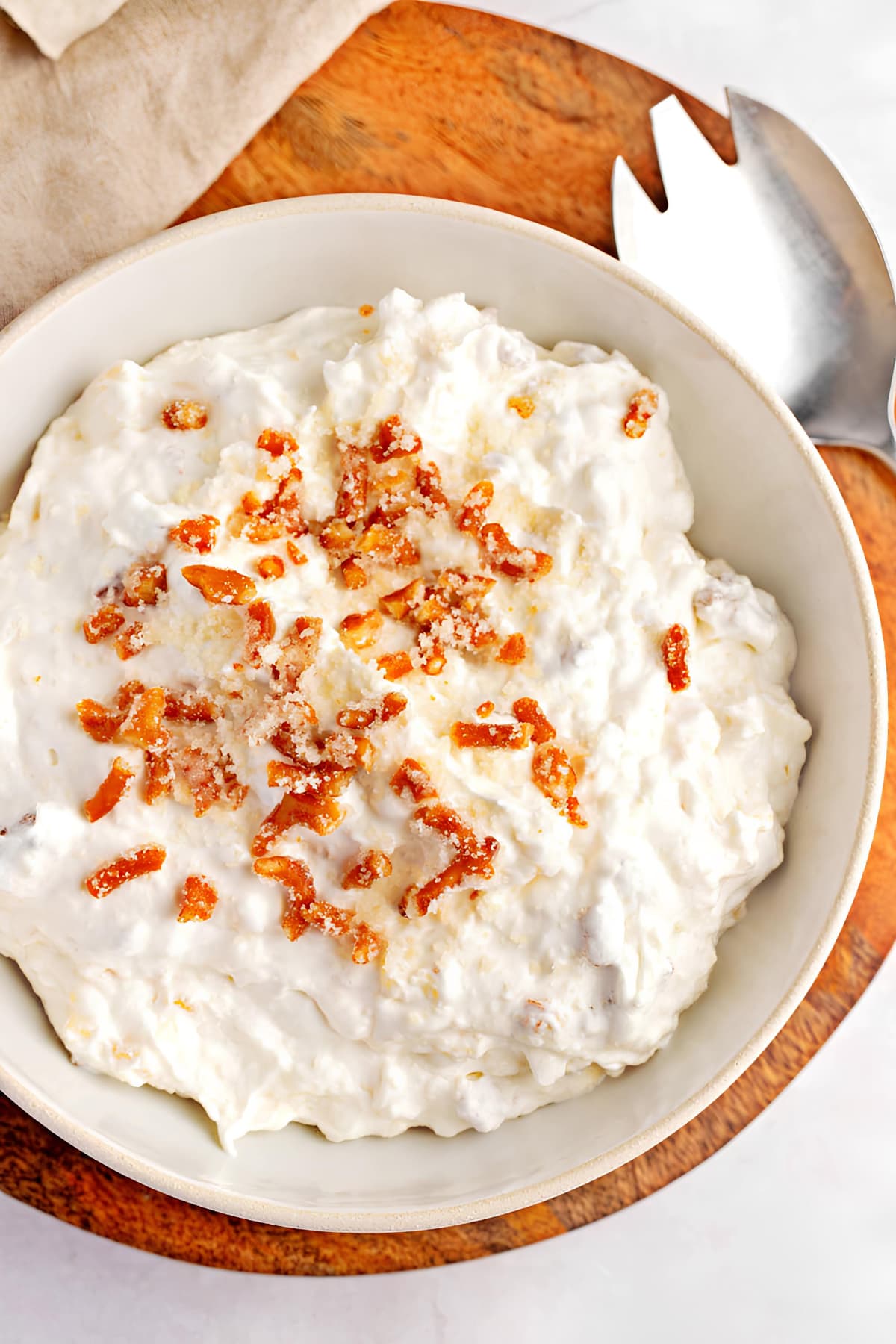 A bowl of pineapple pretzel fluff garnished with crushed pretzels. 