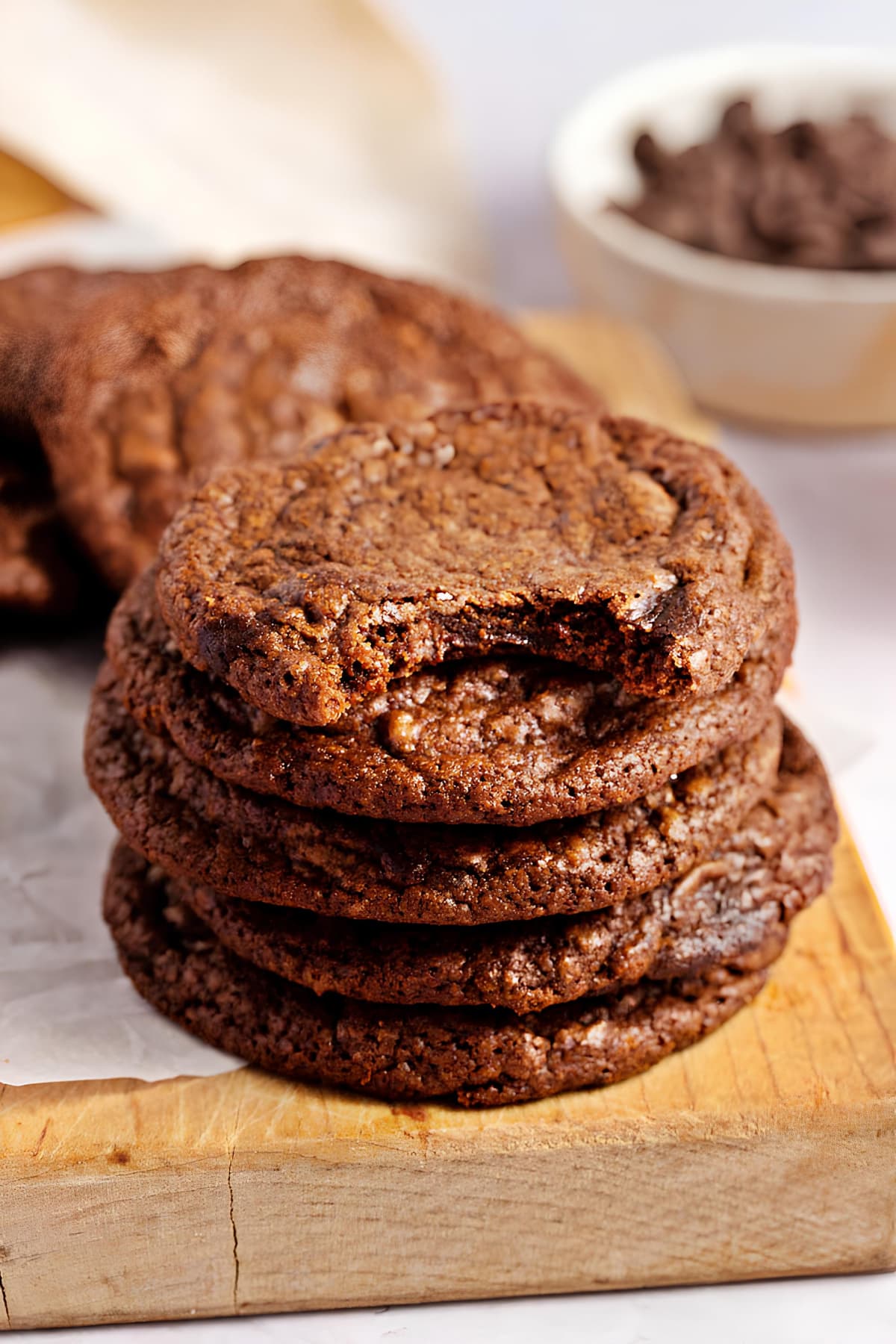 Stacked brownie cookies on a wooden board, top cookie has a bite out of it.