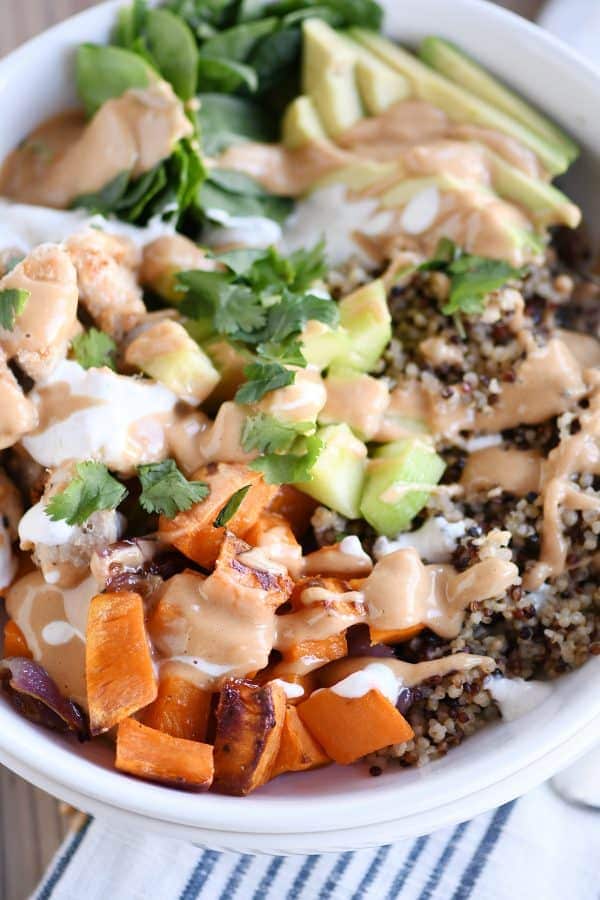 A nutritious bowl of sweet potato and quinoa topped with peanut sauce