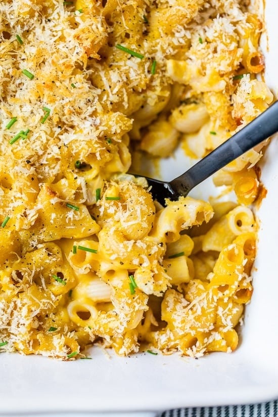 Butternut squash mac and cheese in a casserole with grated parmesan cheese on top. 