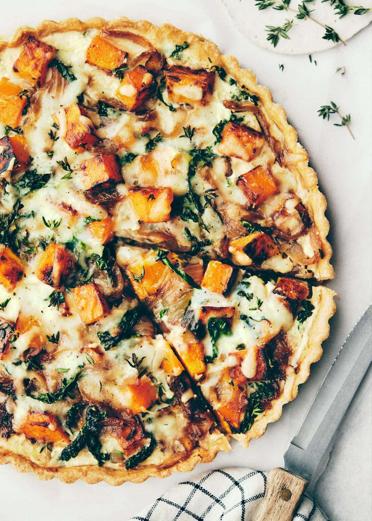 Sliced quiche with caramelized onions, golden butternut squash, thyme, kale topped with melted Gruyere cheese.