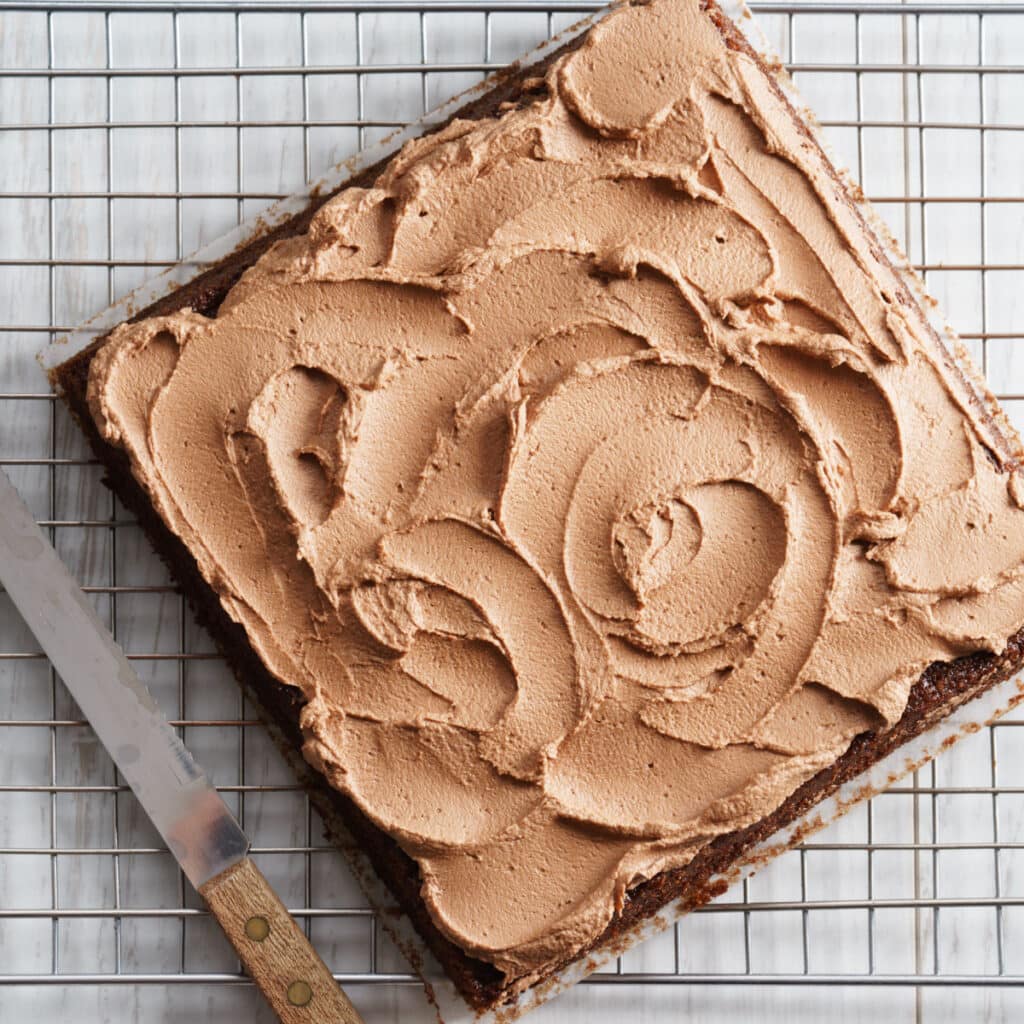 Chocolate Depression Cake with buttercream frosting spread on a cooling rack. 