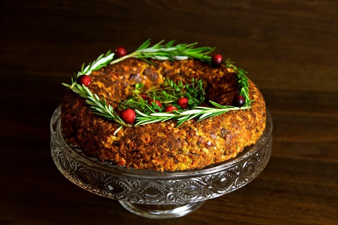 Round shaped cashew and nut roast on a glass cake tray.