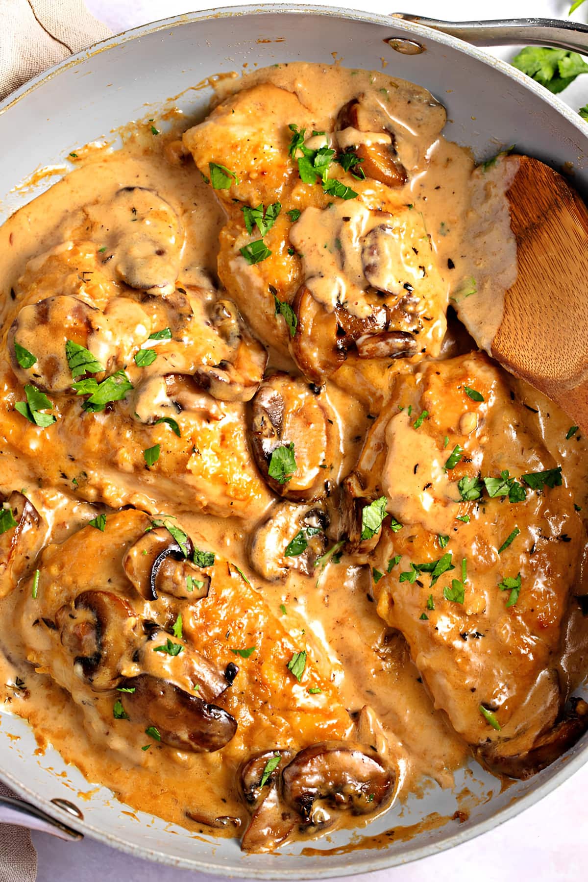 Creamy chicken masala on a pan garnished with chopped parsley leaves.