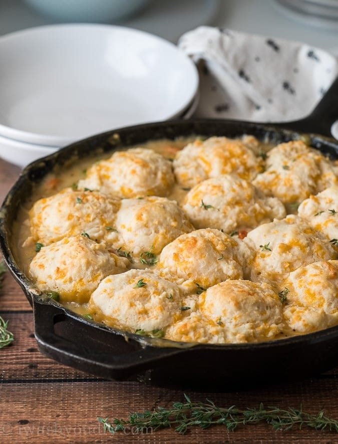 Whole chicken pot pie garnished with fresh thyme leaves cooked in a cast iron skillet. 