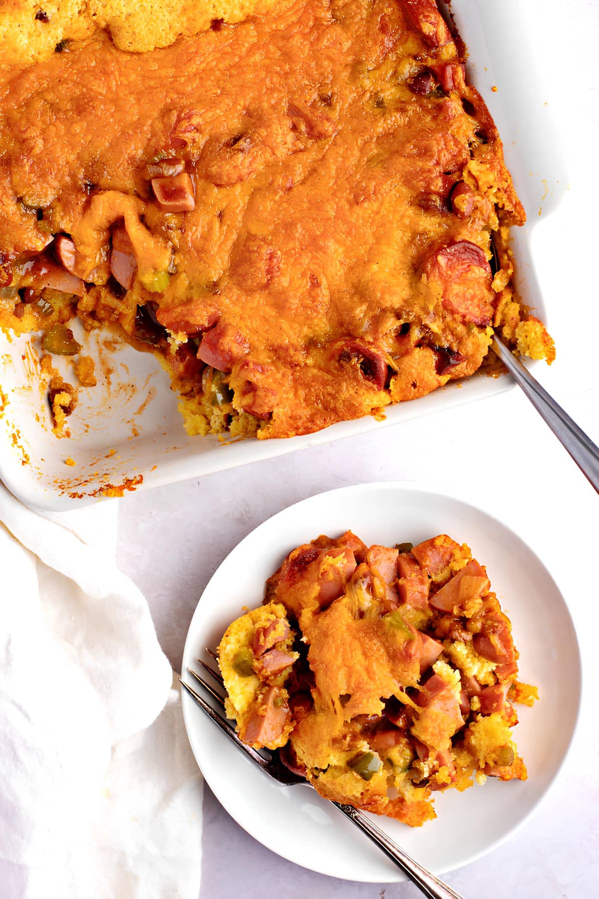 Chili dog casserole on saucer and baking dish.