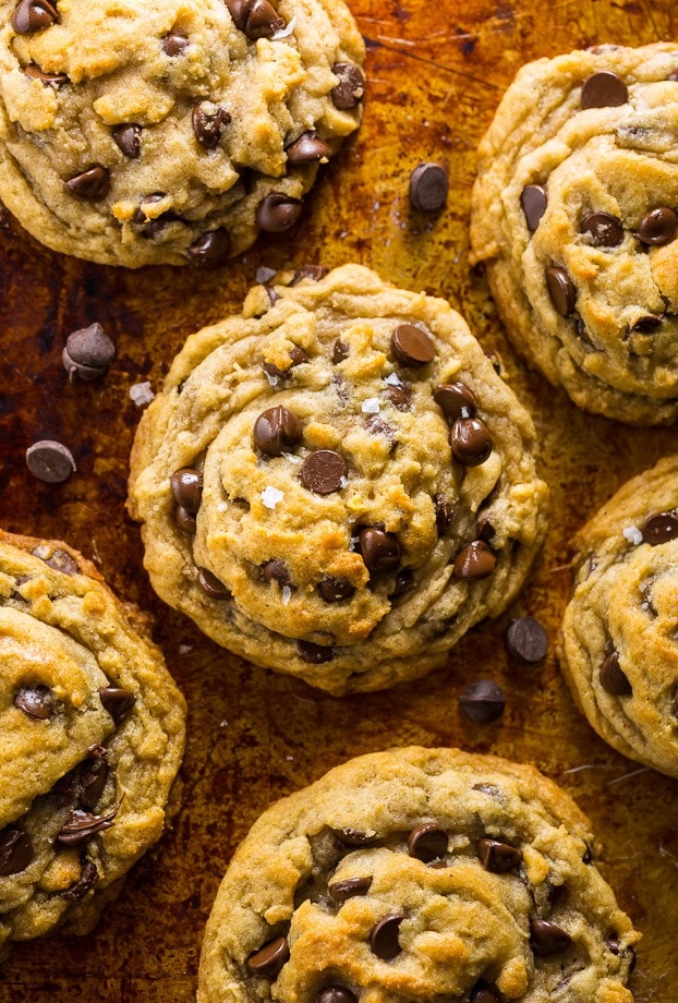 Chocolate chip cookies sprinkled with rock salt flat lay on a wooden surface.