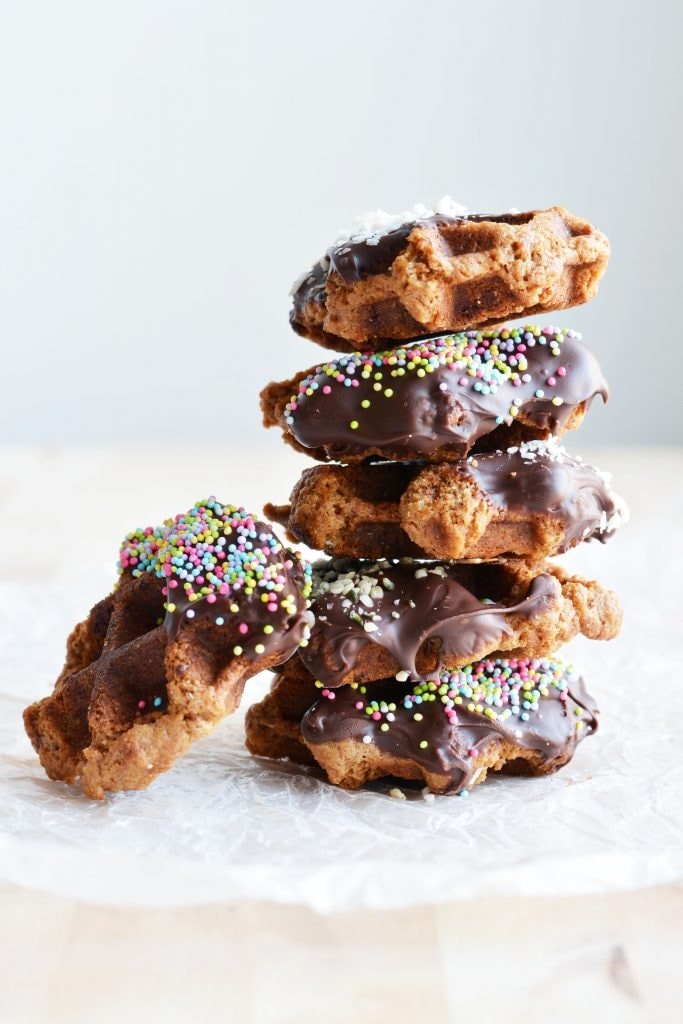 Stack of chocolate colored peanut butter waffle cookies with sprinkles. 