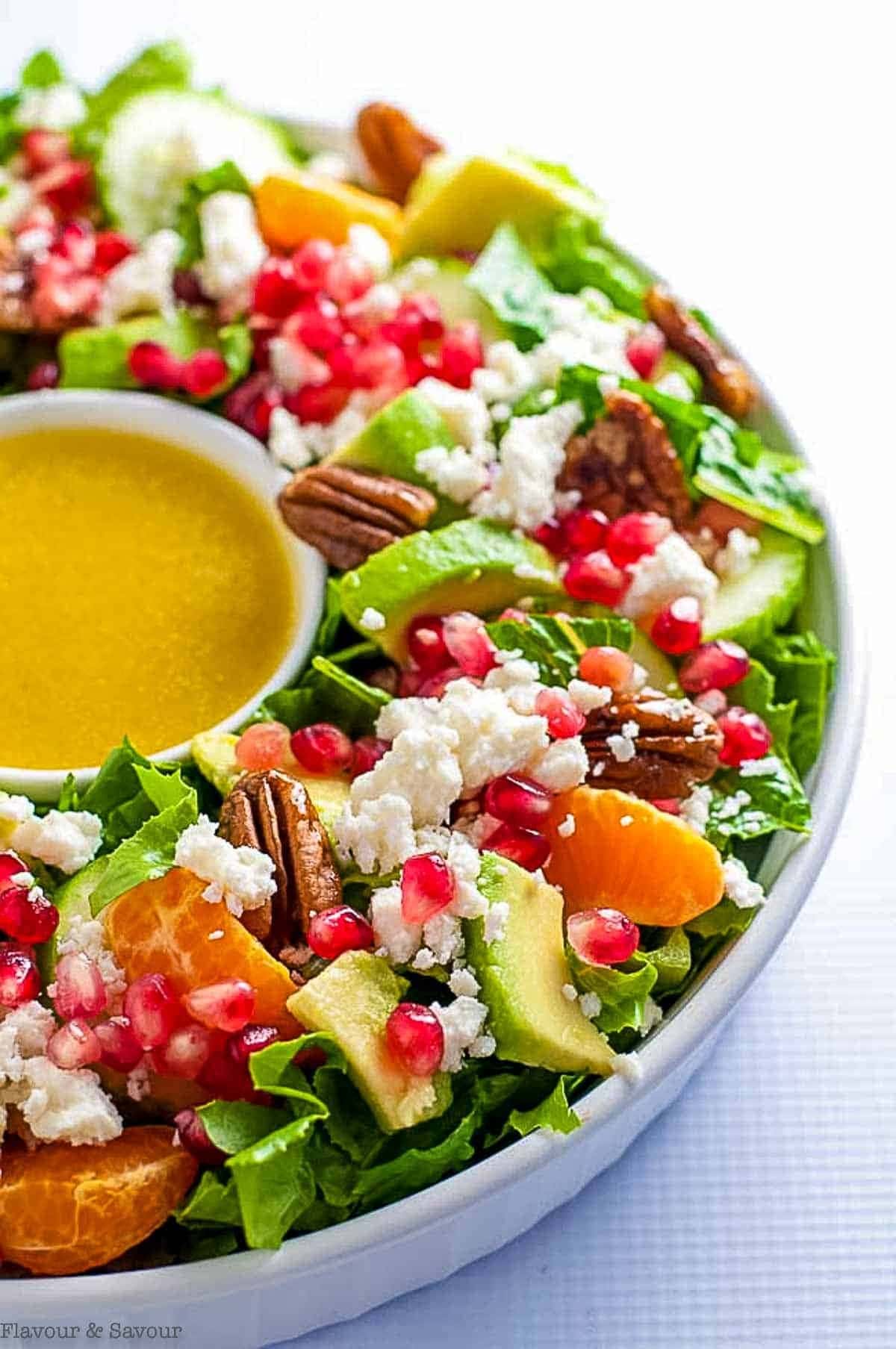 Salad with avocado, crumbly feta, crunchy walnuts, and juicy mandarin oranges in a bowl.