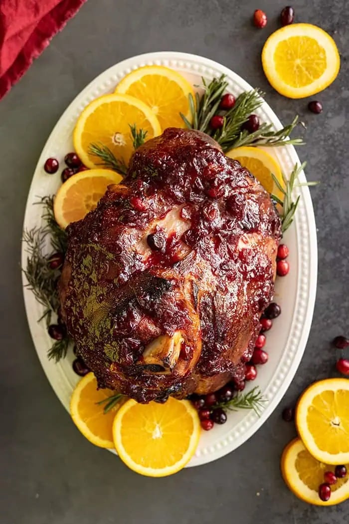 Whole glazed ham garnished with sliced orange and cranberries. 