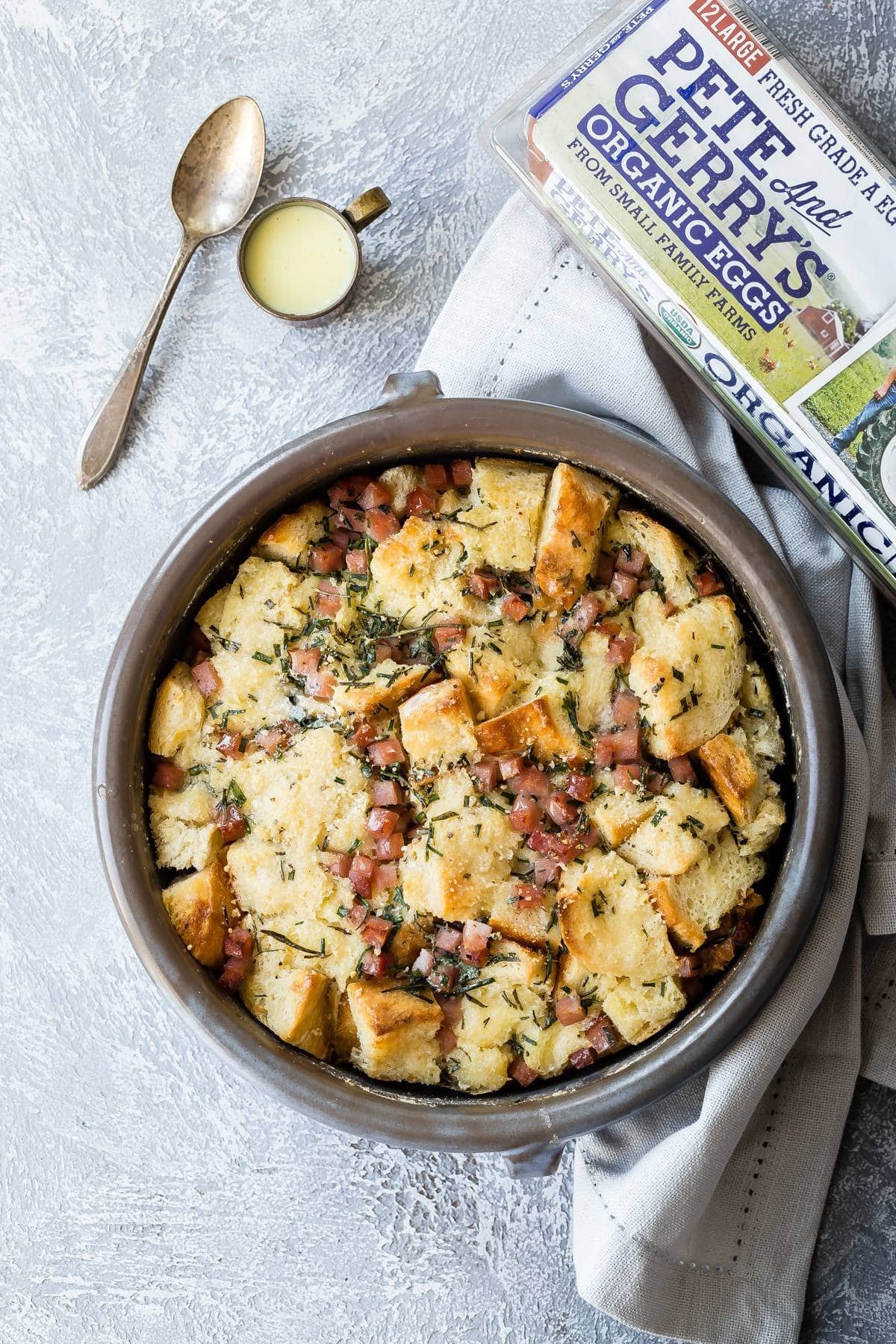 Bread pudding with bacon bits garnished with chopped herbs on pan. 