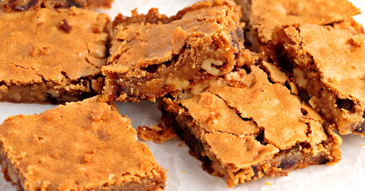 Blondie butterscotch bars on a wooden chopping board with parchment paper.