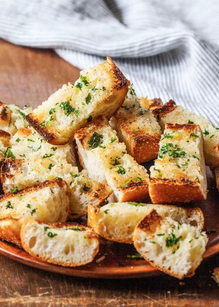 Toasted garlic bread on a brown plate. 