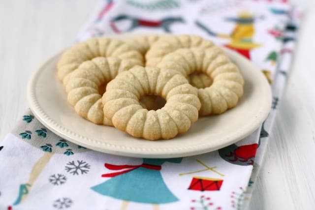 Spritz cookies on a plate dusted with powdered sugar. 