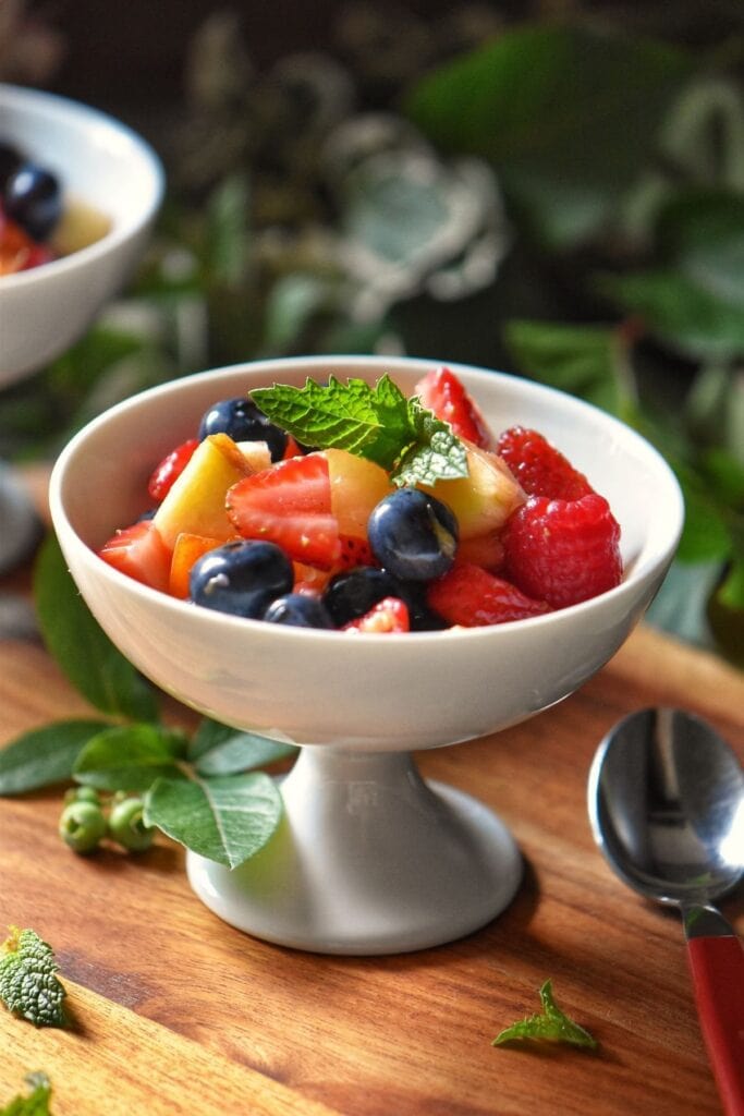 Mixed strawberries, berries and sliced apples in a salad bowl.