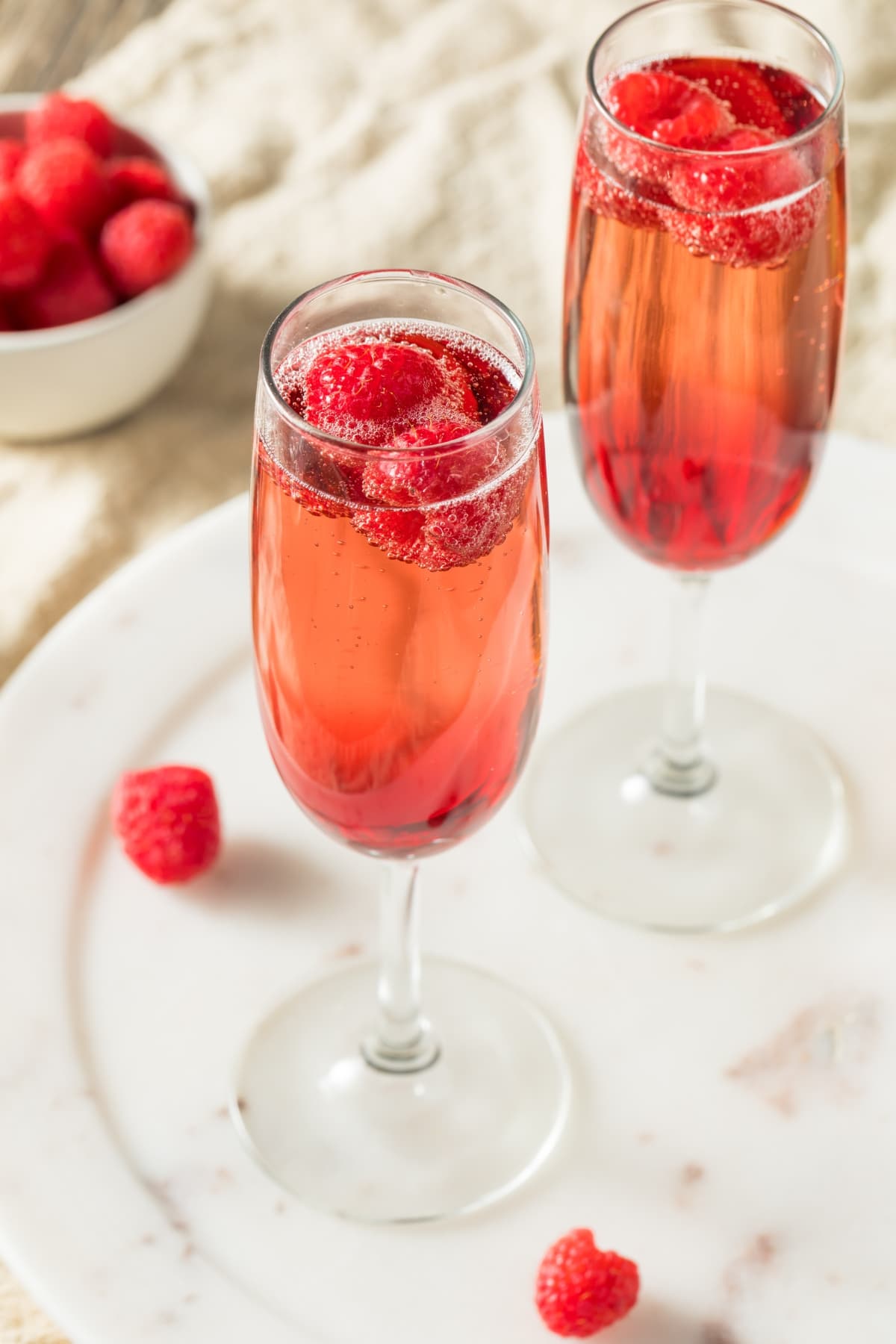 Bubbly, raspberry-infused champagne cocktail with real raspberries on a glass.