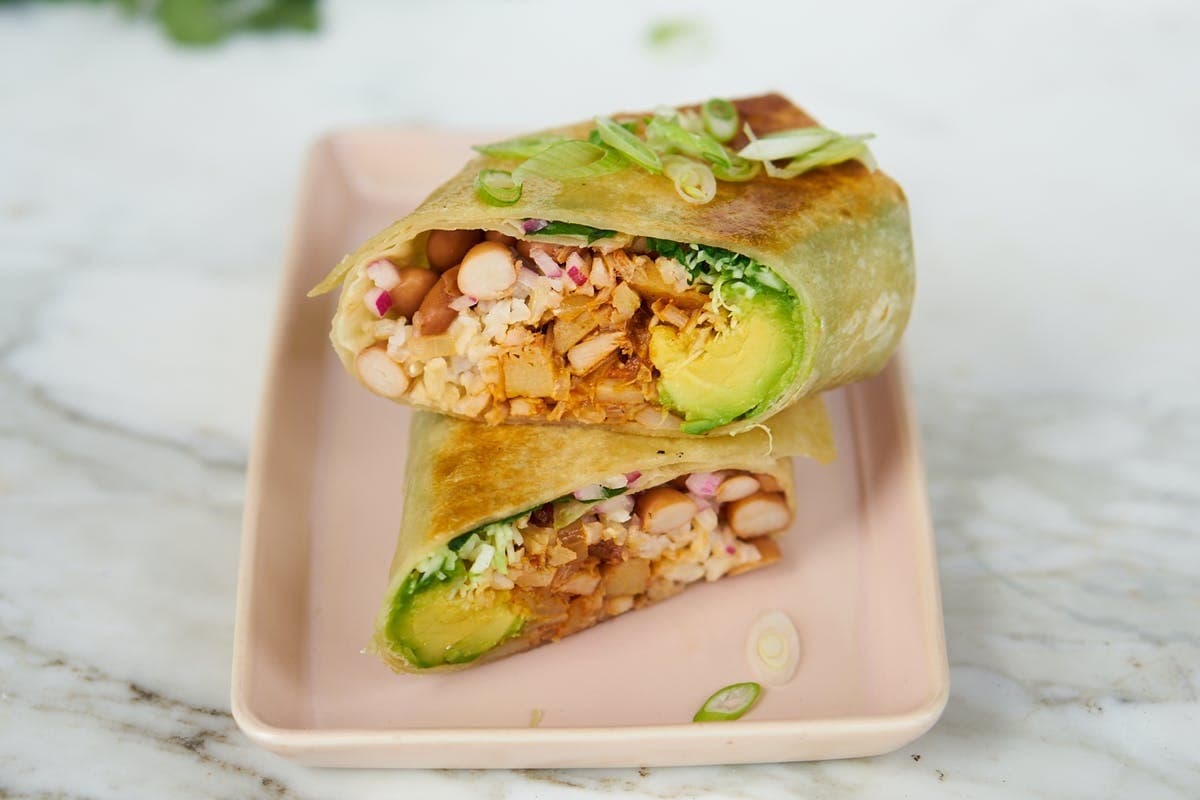 Sliced in half burrito with jackfruit and avocado filling.