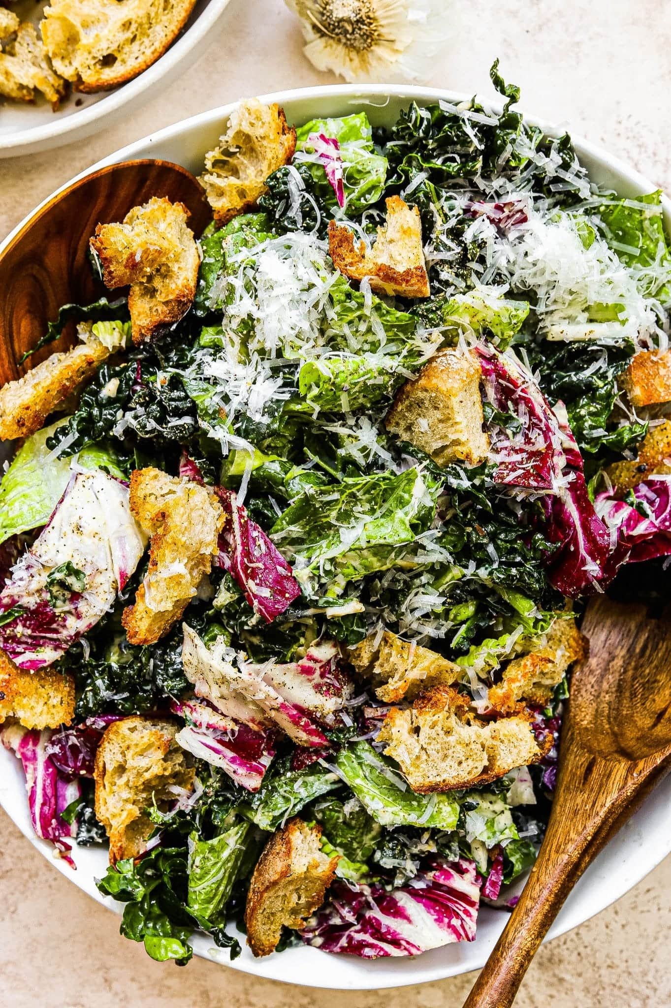 Kale salad with croutons, cabbage and cheese on a wooden bowl. 