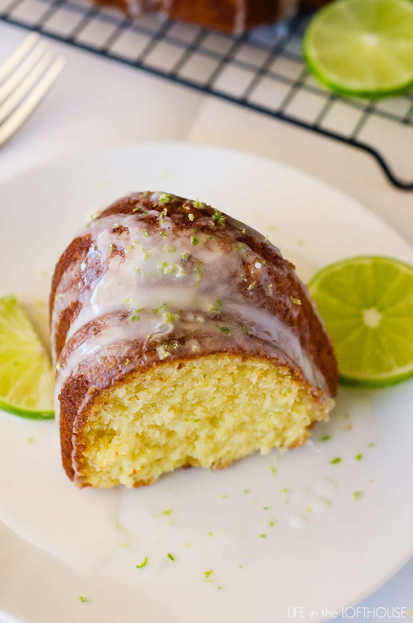 Slice of key lime Bundt cake on a plate with lime glaze and slices of lime. 