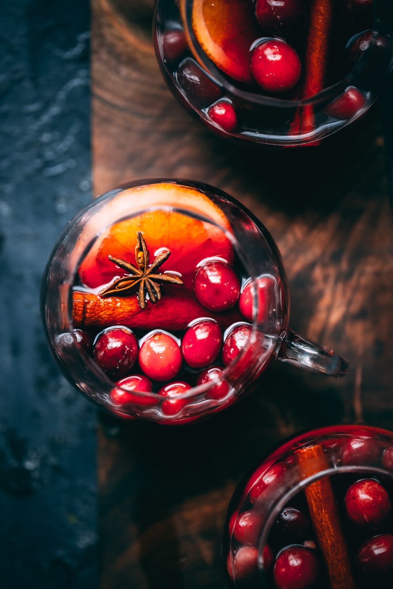 Top view of a glass of cranberry and orange mulled wine, garnished with cinnamon sticks and orange slices.