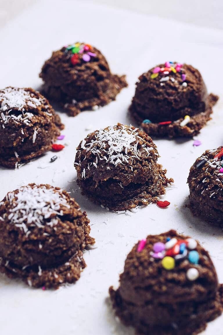 Paleo cookie balls garnished with shredded coconut and candy sprinkles.