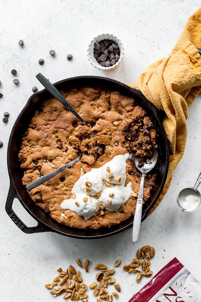 Chocolate chip cookie skillet with a golden brown crust and scoops of ice cream on top with nuts