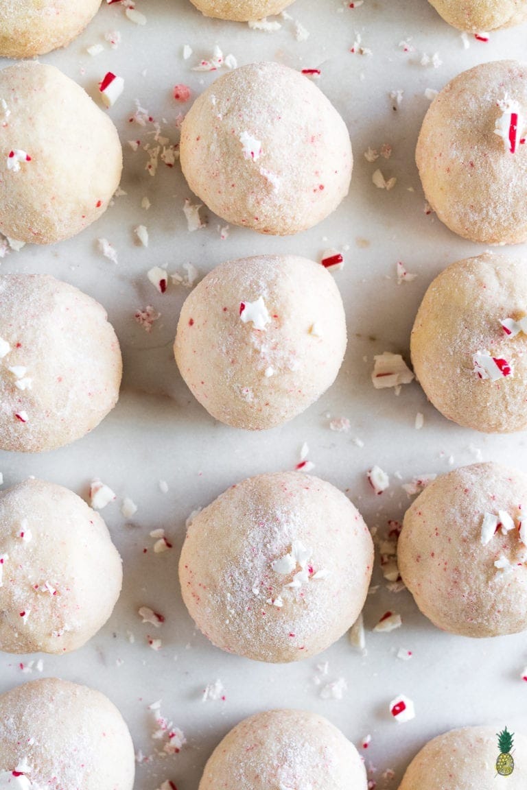 Powdered sugar coated cookie balls with crushed peppermint sugar cane candies.