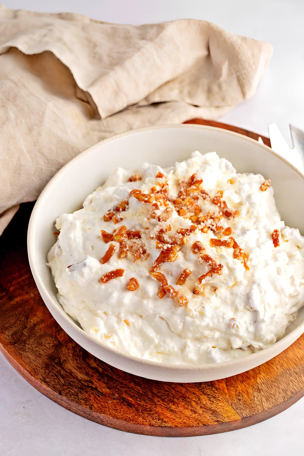 Easy Pineapple Pretzel Fluff (Dessert Salad) featuring Pineapple pretzel fluff in a bowl topped with chopped pretzels. 