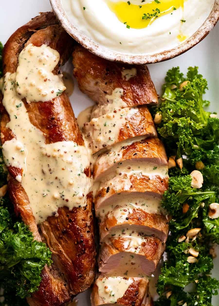 Sliced baked pork tenderloin drizzled with mustard sauce.