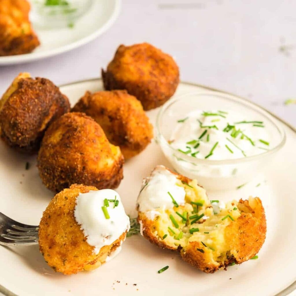 Croquettes served on a plate with dipping sauce. 