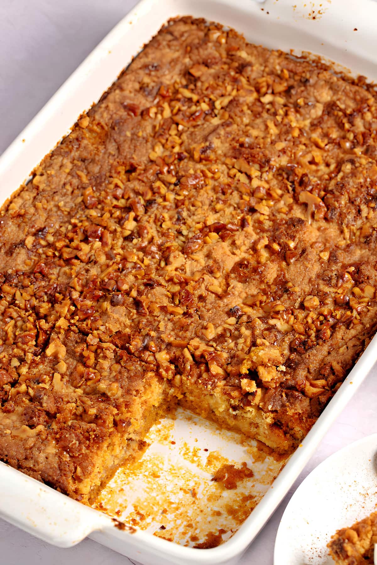 Pumpkin Dessert With Yellow Cake Mix in a casserole dish with a slice missing