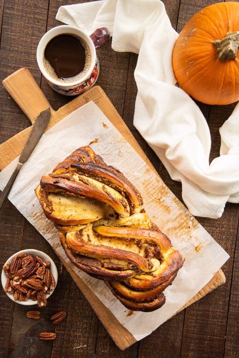 Pumpkin-pecan babka with cinnamon-maple glaze on a wooden board. 