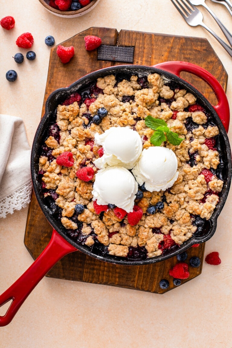 Cobbler on a skillet with raspberry, blueberries and three scoop of ice cream on top