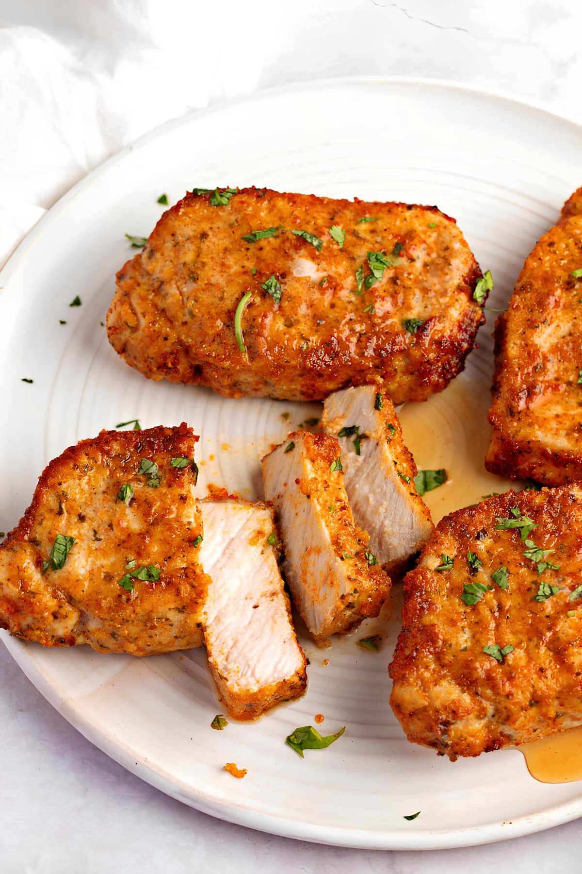 Sliced breaded pork chops with chopped parsley leaves garnish on top. 