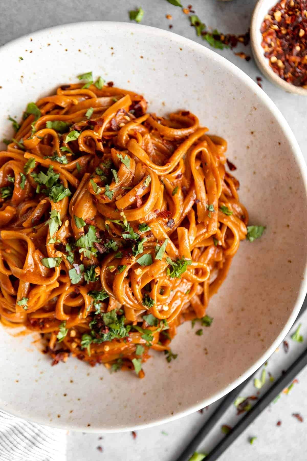 Thai noodles with curry sauce garnished with chopped Parsley and chili flakes.