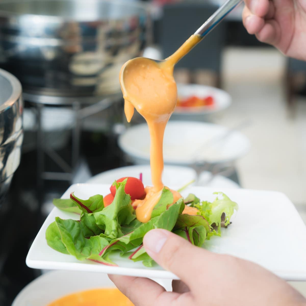 A Person Holding Pouring a Thousand Island Dressing Over a Garden Salad