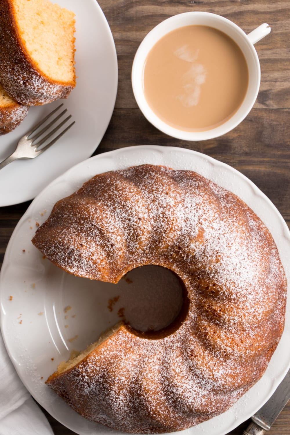 Top view of a whole and a serving crack cake on a plate with a cup of coffee.